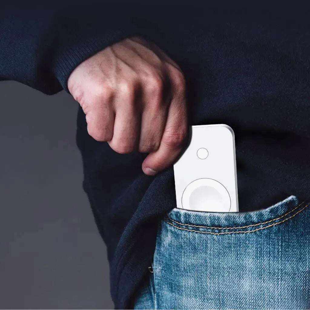Compact white Apple Watch keychain power bank being placed into jeans pocket by hand